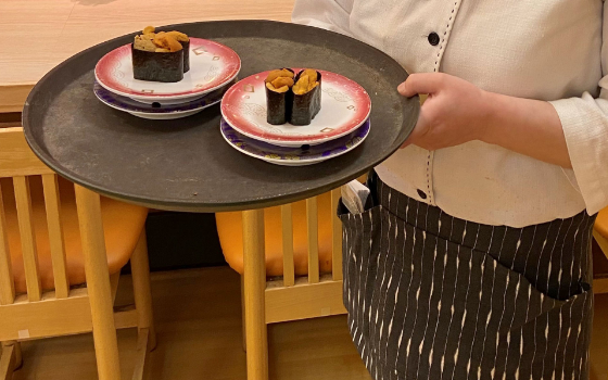 ホールで寿司を配っているスタッフ